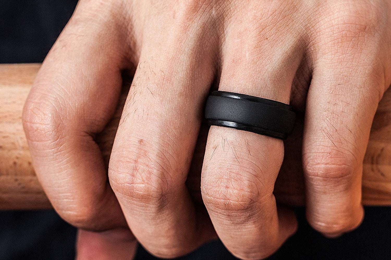 Guys hand holding wood wearing our Black Step Edge Men's Silicone Rings. The Best Silicone Rings For Men Online.